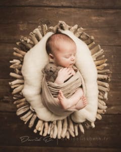 bébé emmaillotté dans une corbeille en bois