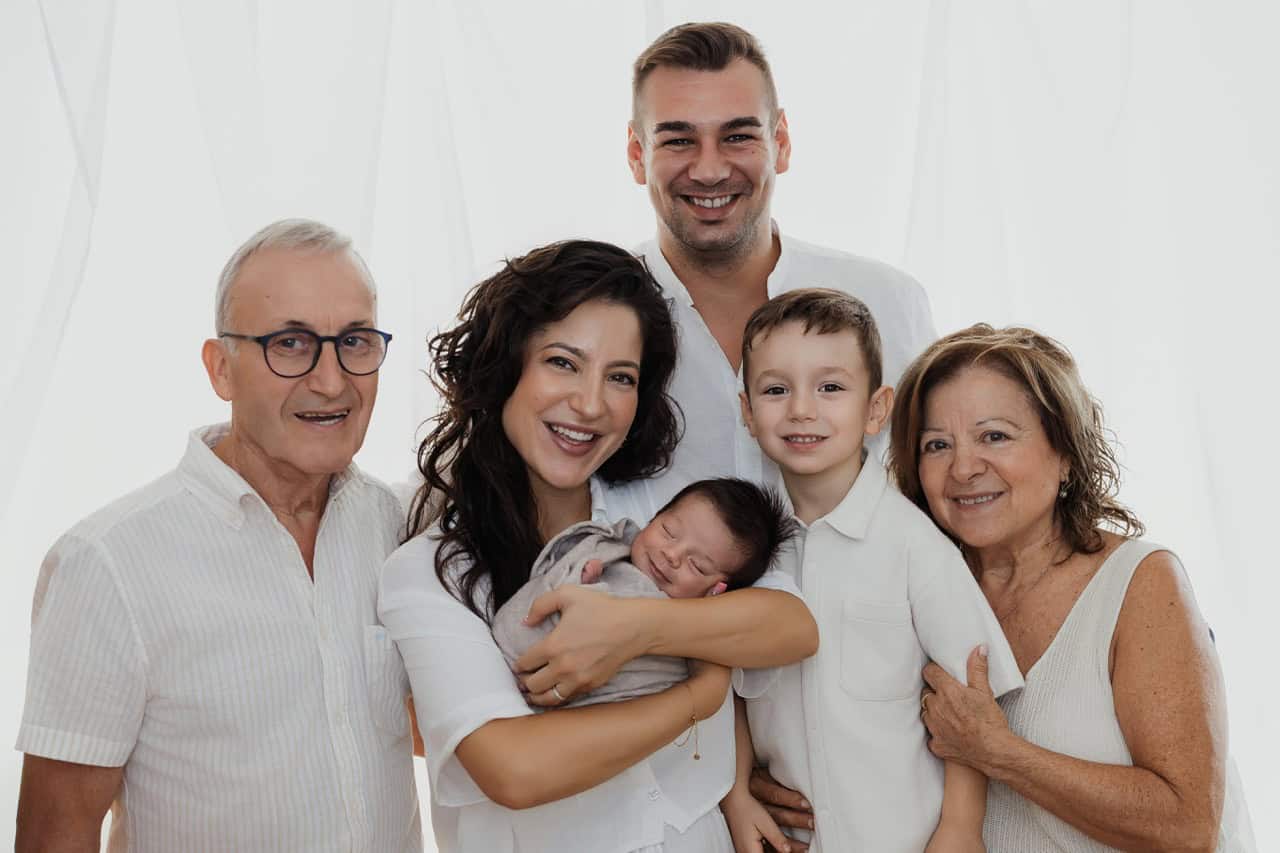 Portrait de famille au studio avec un nouveau-né dans les bras de sa maman